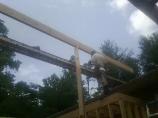 Carpenter setting a ridge beam over a new addition frame — Ice Dam Removal by Roofing Brothers in Nashport