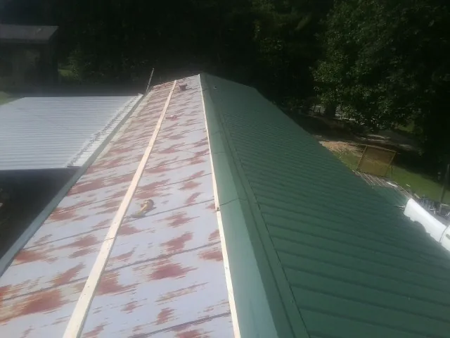 Old rusted panels beside newly installed green metal roofing — Wind Damage Roof Repair by Roofing Brothers in Nashport
