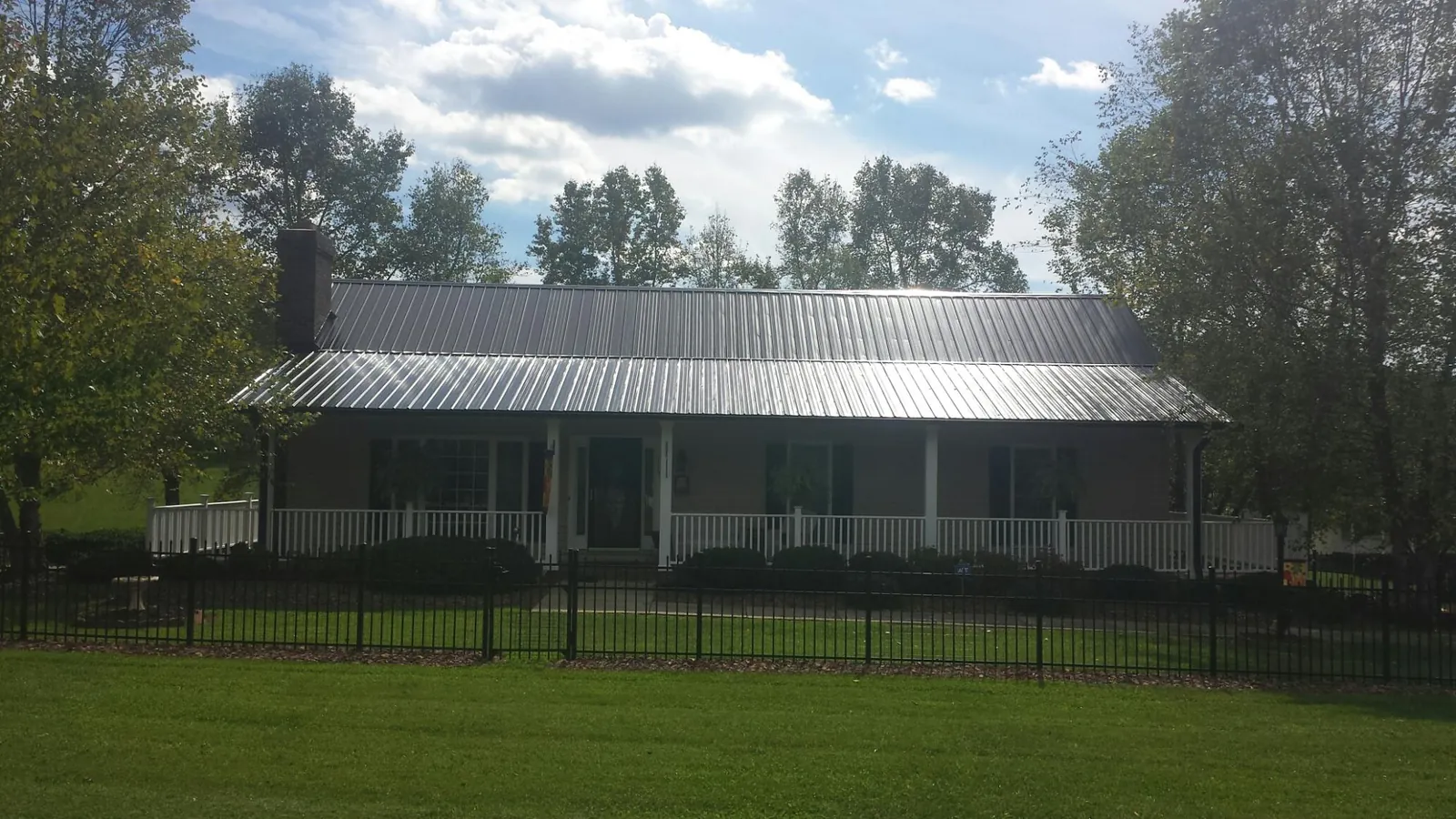 Gray metal roof on a brick ranch with a full width front porch — Gutter Guard Installation work by our crew in Nashport