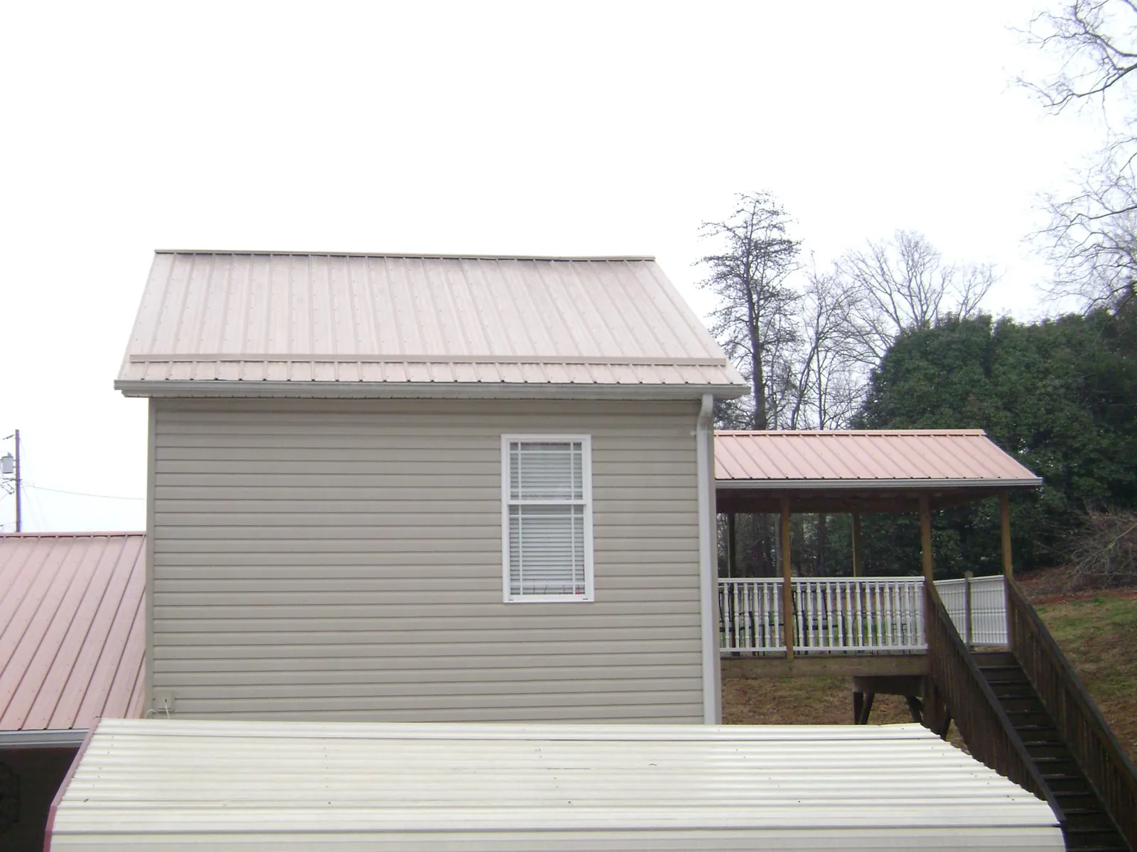 Tan metal roofs on a two story addition and attached porch, from a Roof Replacement job in Nashport