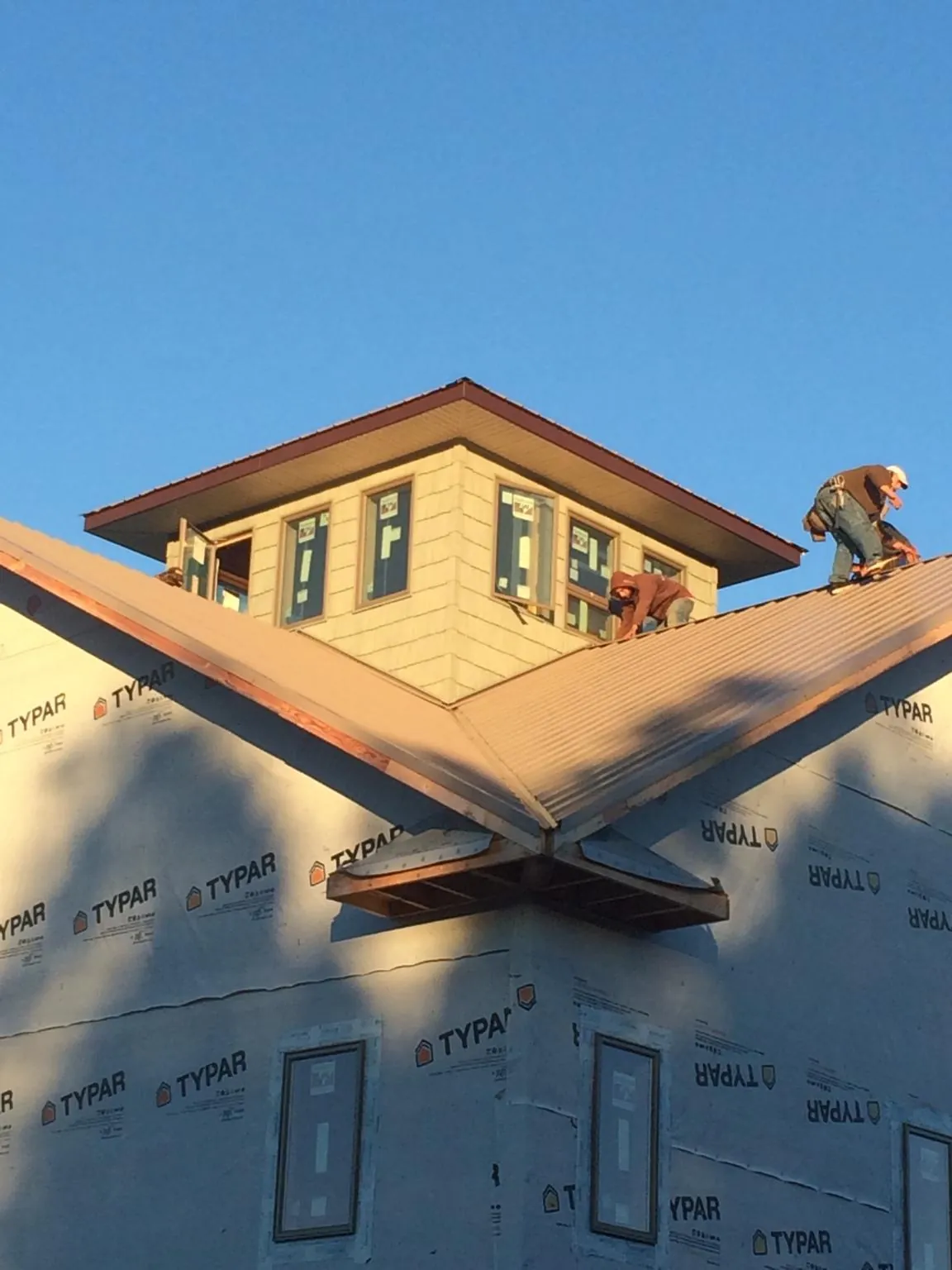 Roofers working around a rooftop cupola on a new metal roof at sunset — Roof Waterproofing in Nashport by Roofing Brothers